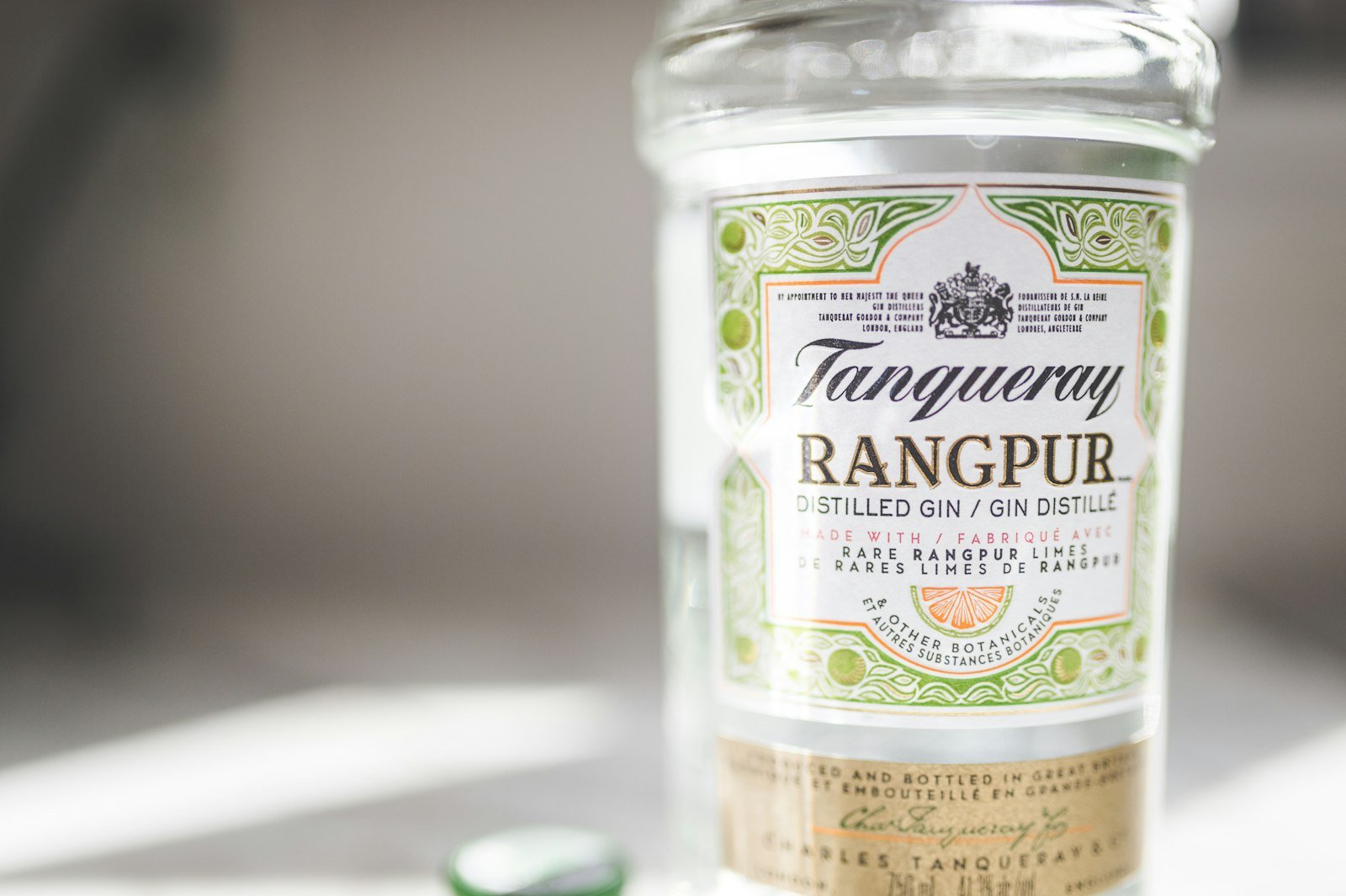 Tasting notes for Tanqueray London Dry Gin, bottle on a clean surface with a gin and tonic garnished with lime